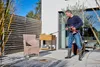 A man is pressure washing a chair on a patio. Produktbild-Vorschau