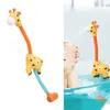 A baby playing with a giraffe-shaped bath toy that sprays water. Produktbild-Vorschau
