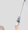 A person's head and shoulder are visible at the bottom left, with a hand holding a white vacuum cleaner with a clear dustbin and a brush attachment at the end of a telescopic tube. Produktbild-Vorschau