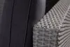 A close-up view of a grey rattan armchair armrest next to a dark grey cushion. Produktbild-Vorschau