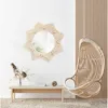 A boho-themed room with a macrame wall mirror, a hanging rattan chair, and a wooden bench with decor. Podgląd zdjęcia produktu