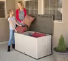 A woman and a girl are putting pillows into a large storage box on a patio. Podgląd zdjęcia produktu