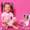 A young girl is sitting on a pink background, playing with a makeup set and nail polish. Produktbild-Vorschau