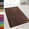 A dark brown shaggy rug is laid out on a light-colored wooden floor in a room with white curtains and a white nightstand in the background. Anteprima dell’immagine prodotto