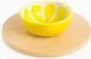 A yellow bowl shaped like a lemon slice sits on a round wooden cutting board against a white background. Podgląd zdjęcia produktu