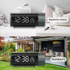 A collage showing a digital alarm clock in two different settings: indoors on a table and outdoors on the grass. Podgląd zdjęcia produktu