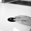 A hand is touching a black circular control panel with digital readouts on a white surface. Produktbild-Vorschau