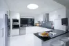 A modern, white kitchen with stainless steel appliances and a black countertop. Podgląd zdjęcia produktu