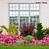A garden border made of wood in front of a house with a window and flowers. Voir les images du produit