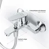 A chrome-finished bathtub faucet mounted on a white tiled wall, with measurement indicators for installation. Produktbild-Vorschau
