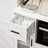 A close-up view of an open drawer in a white sideboard, revealing several white cups stored inside. An espresso machine is visible on the surface above the drawer. Anteprima dell’immagine prodotto