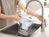 A person is filling a Brita water filter pitcher under a faucet in a sink. Náhled obrázku produktu