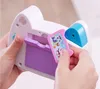 A close-up shot of a person's hands holding a toy camera and inserting a card into it. Produktbild-Vorschau