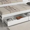 A close-up view of the bottom drawers of a white daybed, showing storage contents. Produktbild-Vorschau