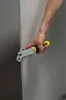 A person's hand is holding a tool to cut a drywall panel. Náhled obrázku produktu