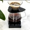 A close-up shot of a pour-over coffee maker with coffee brewing, placed on a digital scale. Produktbild-Vorschau