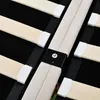 A close-up view of a wooden bed frame with a beige fabric middle section and black support beams. Produktbild-Vorschau