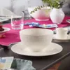 A table setting with a bowl, saucer, cup, and grapes. Náhled obrázku produktu