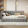 A gray upholstered bed with pillows and a throw blanket. Produktbild-Vorschau
