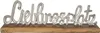 A silver-colored metal word art spelling "Lieblingsplatz" (German for favorite place) is mounted on a wooden base. Produktbild-Vorschau