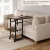 A mobile side table with shelves is placed next to a sofa in a living room. Produktbild-Vorschau