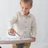 A young boy is playing with a toy ironing board and iron. Produktbild-Vorschau