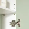 A close-up view of a cabinet hinge and shelf supports inside a cabinet with a light green exterior. Náhled obrázku produktu