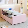 A pink upholstered bed with the mattress lifted to reveal storage space underneath. The headboard has integrated LED lighting. Náhľad obrázku produktu