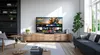 A modern living room with a Panasonic TV on a wooden media console, a sofa, and a bookshelf. Náhľad obrázku produktu