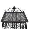 A close-up view of the top of a black metal wine rack with decorative scrollwork and a fleur-de-lis emblem. Náhľad obrázku produktu