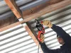 A person is using a drill to make a hole in a wooden beam. Produktbild-Vorschau
