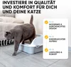 A gray cat is stepping out of a litter box next to a mat. Produktbild-Vorschau