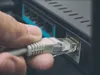 A hand is plugging an Ethernet cable into a router. Náhled obrázku produktu