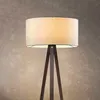 A close-up of a floor lamp with a cream-colored shade and a dark brown tripod base. Produktbild-Vorschau