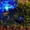 A solar-powered garden spotlight illuminates plants with blue light at night, with a wooden fence in the foreground. Anteprima dell’immagine prodotto