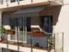 A balcony with a striped awning and flower boxes. Anteprima dell’immagine prodotto
