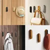 Collage showing different styles and colors of minimalist wall hooks holding various items like hats, bags, and coats. Produktbild-Vorschau