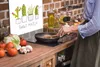 A person is cooking in a kitchen with a glass splashback featuring a cactus illustration. Voir les images du produit