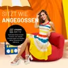 A woman is sitting on a red beanbag chair, with a beach umbrella in the background. There is also a retro-style radio to her left. The image is bright and colorful, with text overlays promoting a product. Produktbild-Vorschau