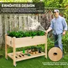 A man watering a raised garden bed in a backyard setting. Produktbild-Vorschau