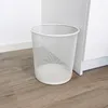 A white mesh waste bin sits on a wooden floor next to a white cabinet. Produktbild-Vorschau