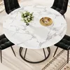 A round dining table with a marble-like pattern and four black chairs are arranged around it on a rug. Produktbild-Vorschau