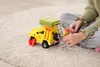 A child is playing with a toy fire truck on a carpeted floor. Produktbild-Vorschau