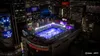 A nighttime aerial view of a rooftop soccer field in a city, illuminated by bright lights. Produktbild-Vorschau