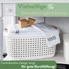 A white laundry basket filled with folded towels and two small wooden cubes, placed on a shelf. Produktbild-Vorschau