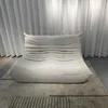 A beige sofa is placed on a rug in front of white curtains. Anteprima dell’immagine prodotto