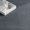 A close-up of a textured gray rug with a geometric pattern, featuring a white tray with a candle and a decorative apple. Anteprima dell’immagine prodotto