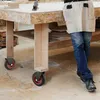 A person wearing jeans and an apron stands next to a workbench with wheels. Voir les images du produit