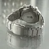 A close-up, angled shot of the back of a silver Festina chronograph watch, showing the clasp and part of the bracelet. The watch is resting on a reflective, textured surface. Náhľad obrázku produktu
