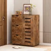 A wooden shoe cabinet with three drawers and two doors, placed in a room with a door and a rug. Podgląd zdjęcia produktu